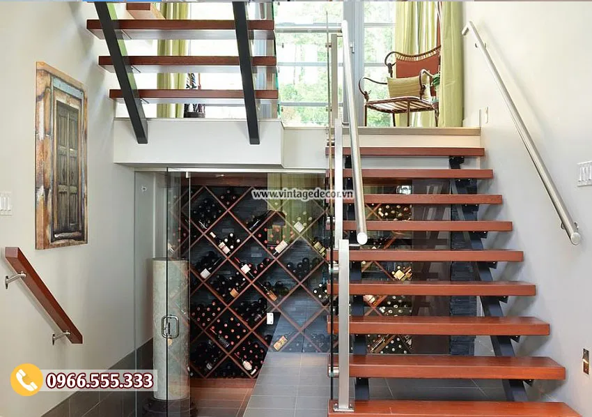 Cầu thang bậc gỗ không cổ bậc, phía dưới là phòng kính có kệ ô chéo chứa chai
