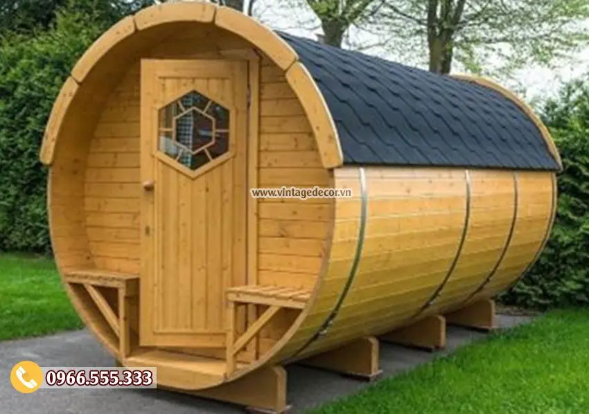 Bungalow dáng thùng gỗ nằm ngang, cửa có ô kính lục giác, hai ghế băng gắn bên cửa