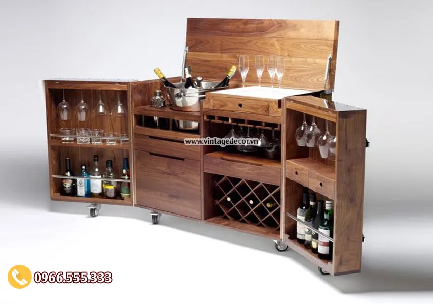 Tủ bar gỗ nắp lật mở lên, hai cánh có ly và chai, giữa là ô chéo xếp chai nằm, chân bánh xe