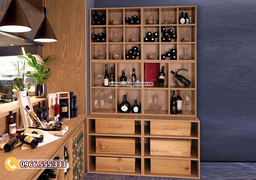 Tủ rượu ô vuông gỗ sáng cạnh quầy, ô trên trưng chai và ly, dưới là ngăn hộp gỗ