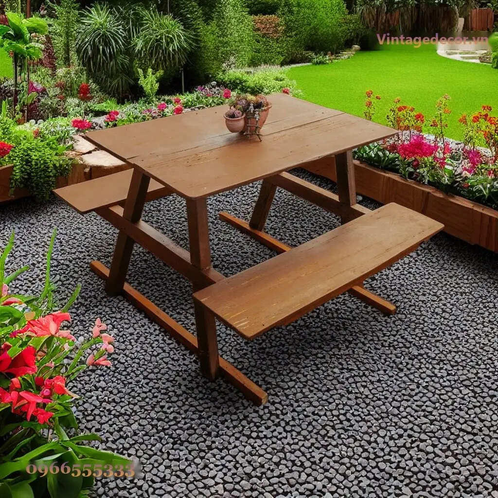 Bàn picnic BG12 mặt rộng trên nền sỏi đen giữa bồn hoa đỏ và bãi cỏ, chậu sen đá nhỏ giữa bàn