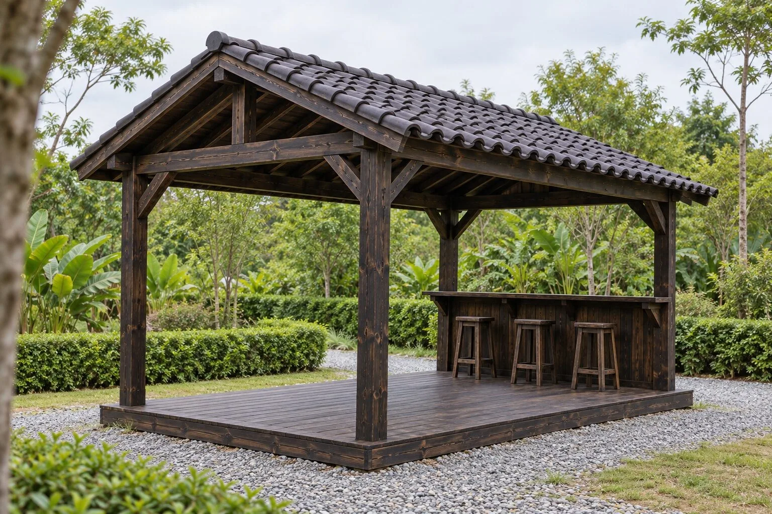 Chòi gỗ T103 màu gỗ sẫm mái ngói hai dốc trên sàn gỗ thấp, quầy bar ván đứng chạy dọc mặt sau với ba ghế đẩu cao, nền sỏi và hàng rào cây xanh