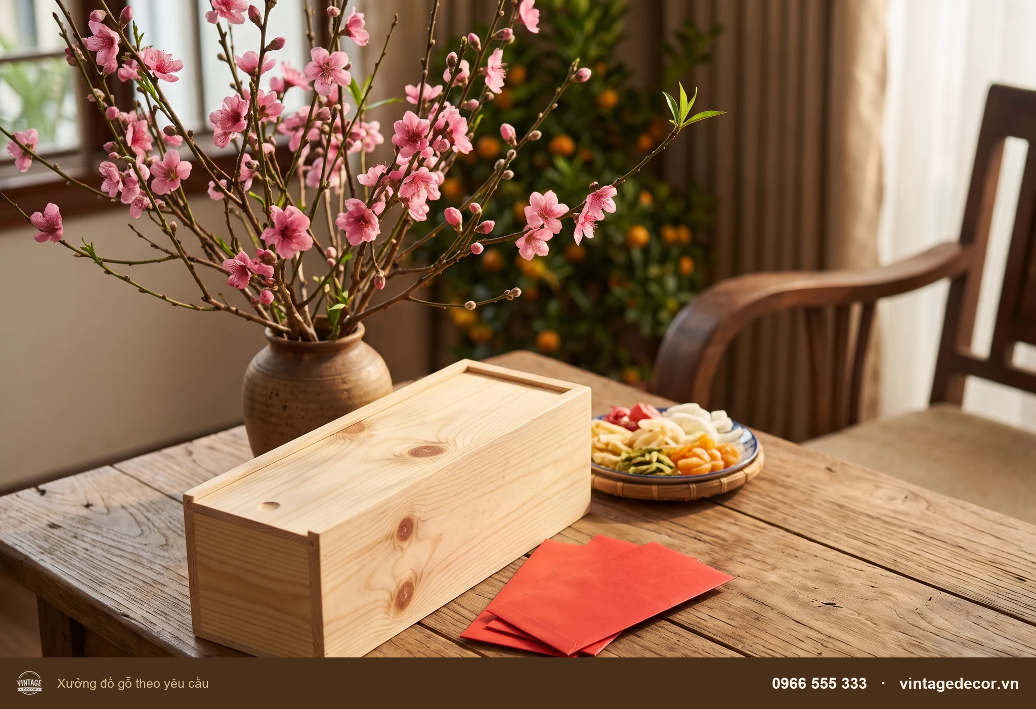 Hộp gỗ thông đựng một chai rượu đặt trên bàn gỗ cạnh cành đào và phong bao đỏ ngày Tết